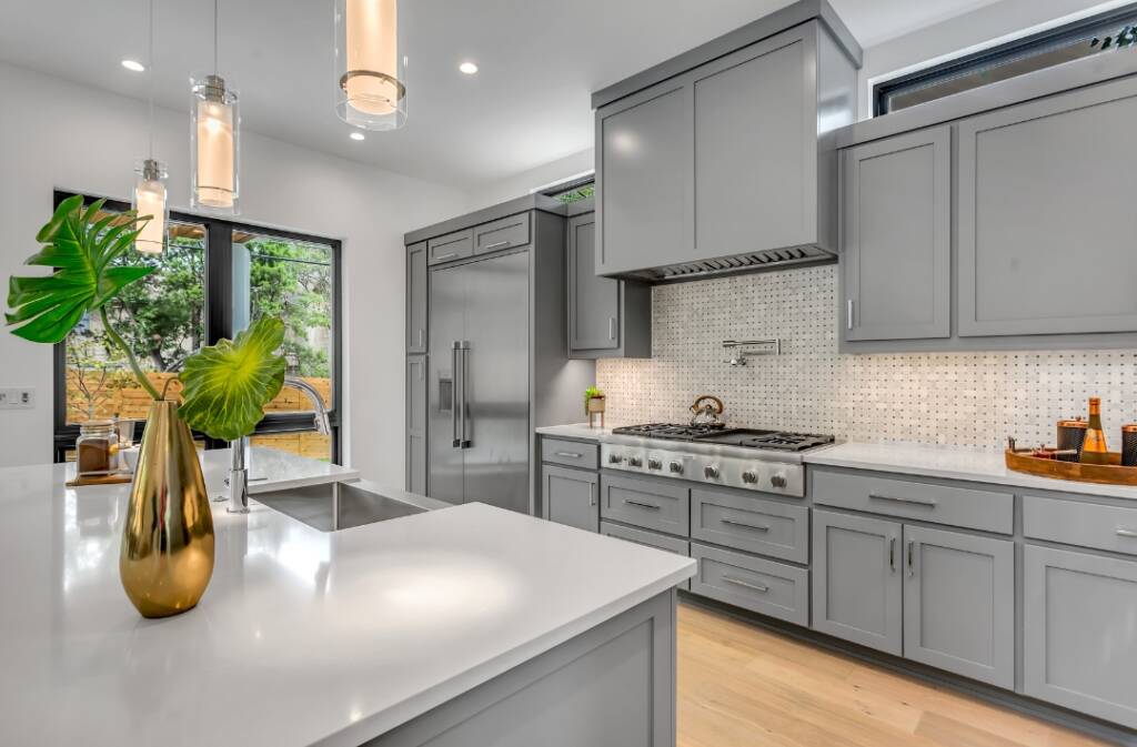 A kitchen with grey cabinets and white counters.