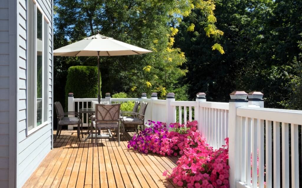 A deck with an umbrella and chairs on it