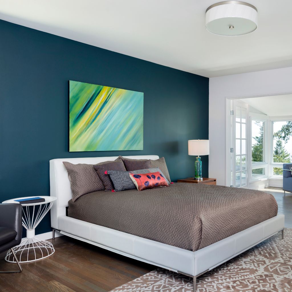 A bedroom with a bed, nightstand and painting.