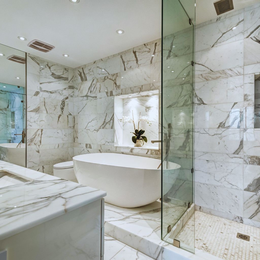 A bathroom with marble walls and floors, a tub and shower.